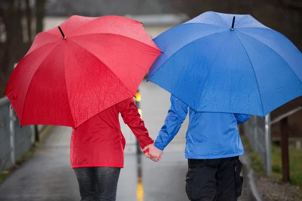 Pareja de mano en mano caminar bajo la lluvia con paraguas —  Fotos de Stock
