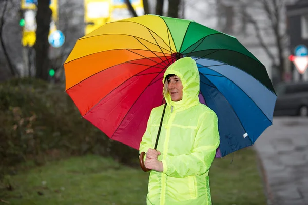 Regengeschützte Frau wartet mit Regenschirm im Regen — Stockfoto