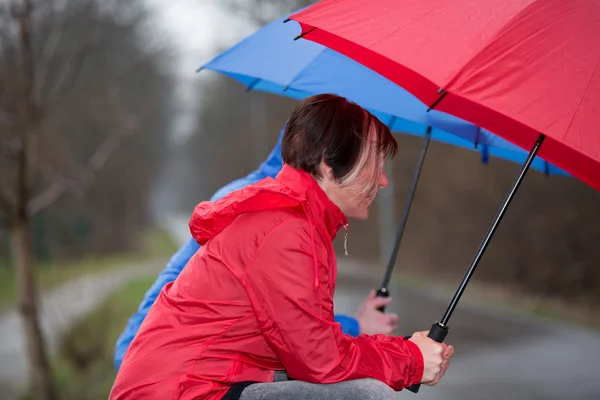 Sentado na chuva, coberto por um guarda-chuva . — Fotografia de Stock