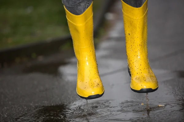 Gumboots are jumping into a water puddle — Stock Photo, Image