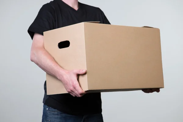 Llevar un cartón pesado con dos manos, aislado en gris — Foto de Stock