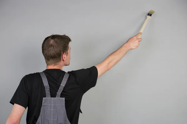 A Painter is using a brush over his head to paint the wall — Stock Photo, Image