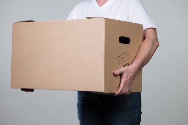 Bir kadın bir ağır karton gri bir arka plan üzerinde taşıyor