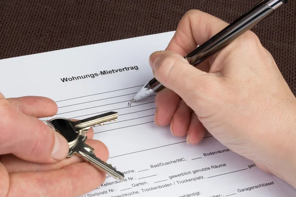 A woman is filling out a german tenancy agreement with keys in h — Stock Photo, Image