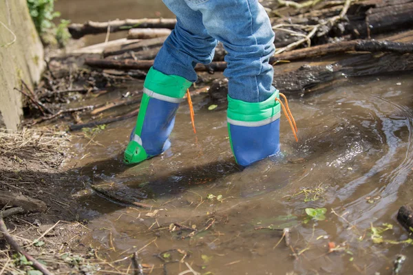 El chico está caminando a través de un pequeño río —  Fotos de Stock