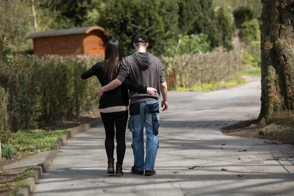 Backview van een paar liefdes lopen in een park. — Stockfoto