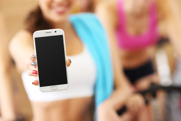 Fit femme tenant smartphone dans la salle de gym — Photo