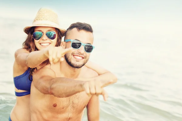 해변에서 가리키는 행복 한 커플 — 스톡 사진
