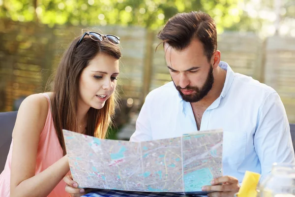 Parejas jóvenes con mapa en la cafetería — Foto de Stock