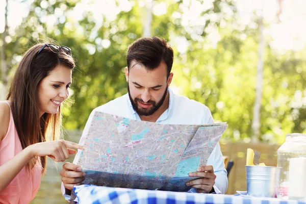 Parejas jóvenes con mapa en la cafetería — Foto de Stock