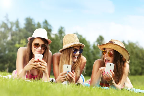 Freunde liegen im Gras und schreiben SMS — Stockfoto