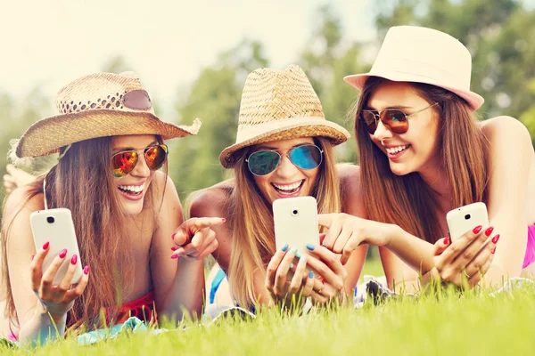 Freunde liegen im Gras und schreiben SMS — Stockfoto