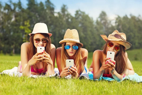 Friends lying on the grass and texting — Stock Photo, Image