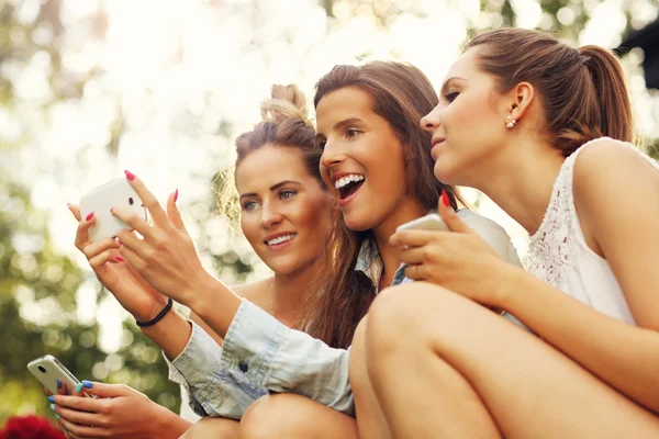 Girlfriends using smartphones — Stock Photo, Image