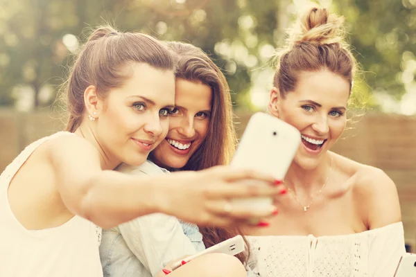 Amigos femininos com smartphones tirando selfie — Fotografia de Stock