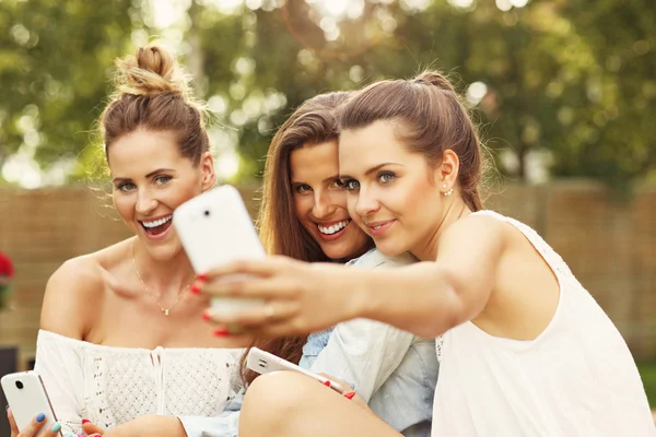 Amigos femininos com smartphones tirando selfie — Fotografia de Stock