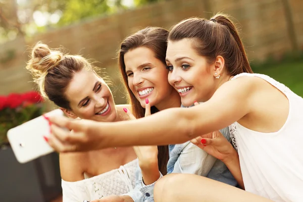 Женщины-подруги со смартфонами делают селфи — стоковое фото