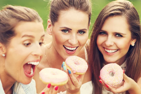 Amigos felizes comendo donuts — Fotografia de Stock