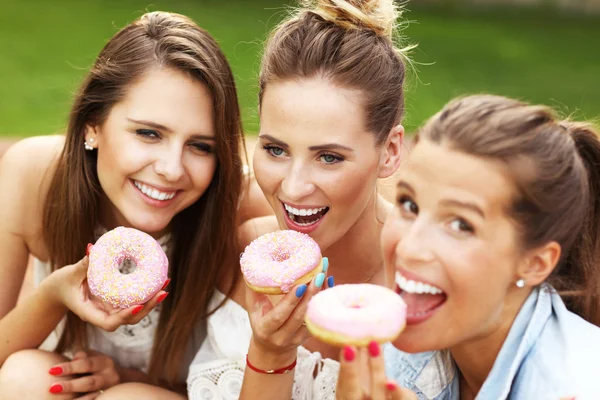 Amigos felizes comendo donuts — Fotografia de Stock