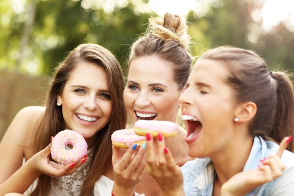 Amigos felizes comendo donuts — Fotografia de Stock