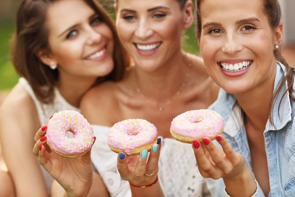 Happy vänner äta munkar — Stockfoto