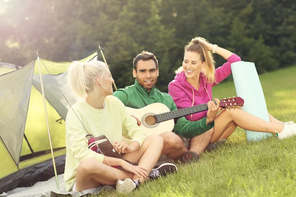 Przyjaciele camping w lesie i gra na gitarze — Zdjęcie stockowe