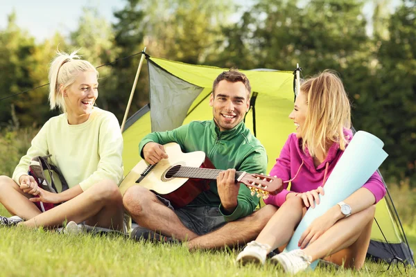 Amici campeggio nella foresta e suonare la chitarra — Foto Stock