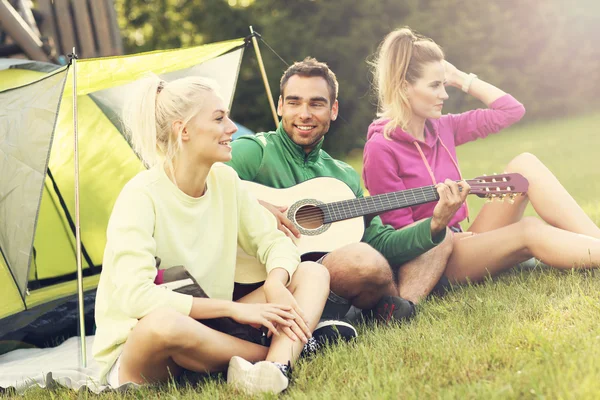 Amici campeggio nella foresta e suonare la chitarra — Foto Stock