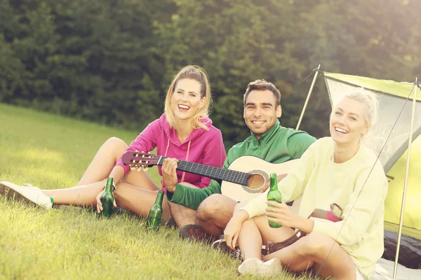 Vrienden kamperen in het bos en gitaar spelen — Stockfoto