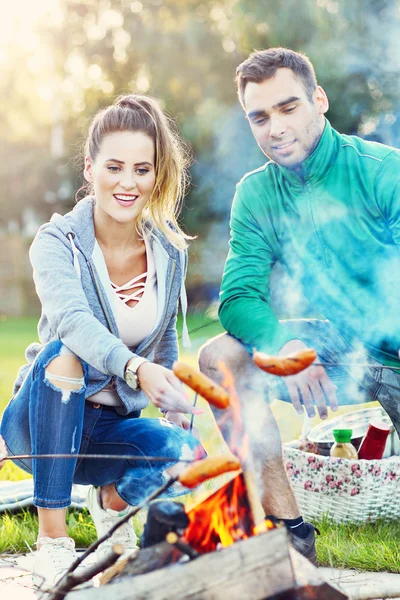 Friends preparing sausages on campfire — Stock Photo, Image