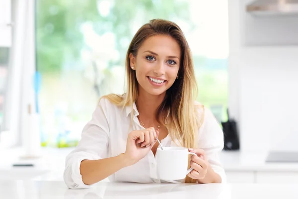 Ung kvinna med kaffe i köket — Stockfoto