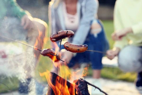 Amigos preparando salsichas na fogueira — Fotografia de Stock