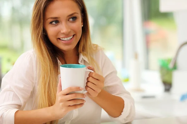 キッチンでコーヒーを持つ若い女性 — ストック写真