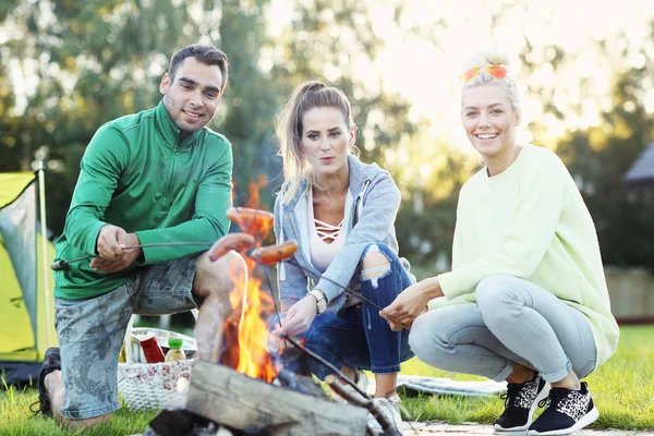 Amici che preparano salsicce sul falò — Foto Stock