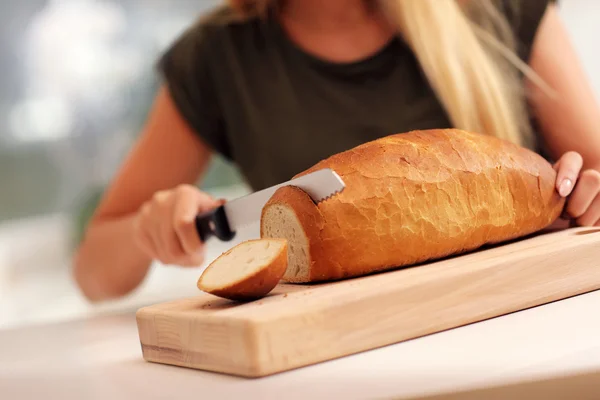 Woman slicing loaf of bread — Stock Photo, Image