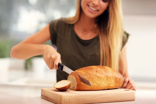 Woman slicing loaf of bread — Stock Photo, Image