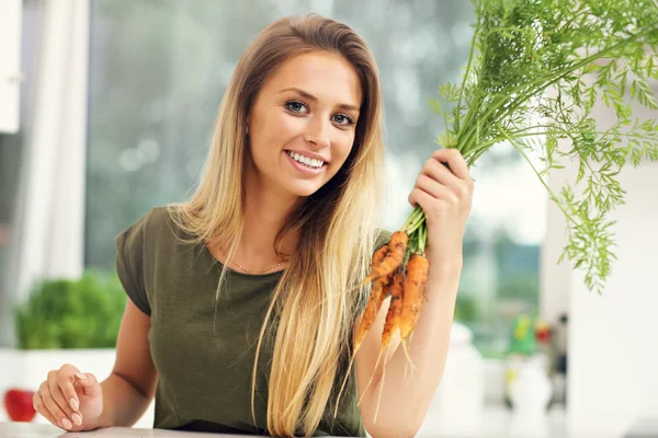 Frau mit frischen Möhren in der Küche — Stockfoto