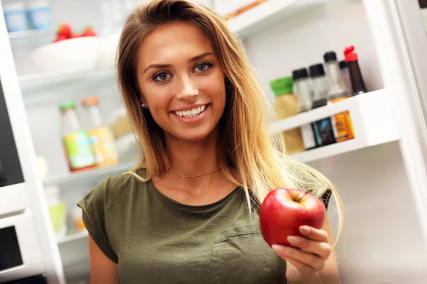 Žena s apple nad lednice — Stock fotografie