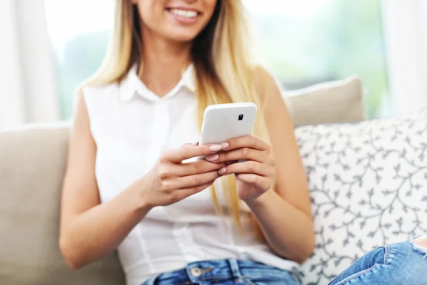 Jeune femme sur canapé avec smartphone — Photo