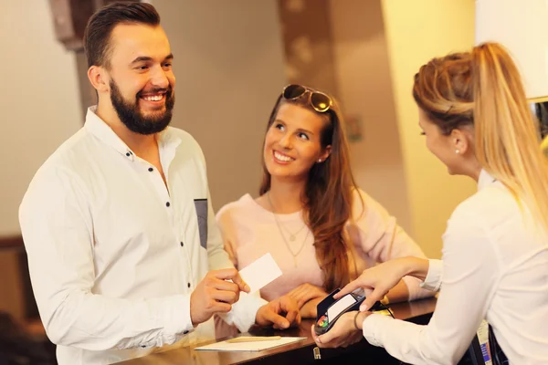 Couple at counter paying for hotel — Stock Photo, Image