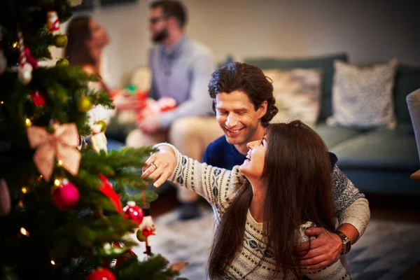 Adultos casais se divertindo sobre a árvore de Natal — Fotografia de Stock