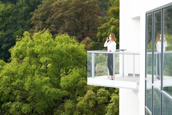 Pebisnis wanita mengenakan topeng berdiri di balkon — Stok Foto