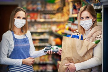 Adult woman in medical mask picking up order in grocery store clipart