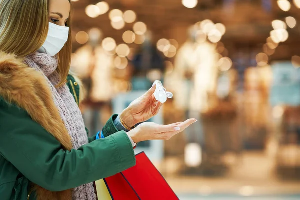 Mittparti av vuxen kvinna i köpcentret bär mask och använder handdesinfektionsmedel — Stockfoto