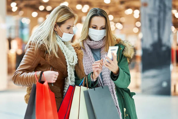 Amigas com compras de smartphones juntos usando máscara coronavirus conceito — Fotografia de Stock