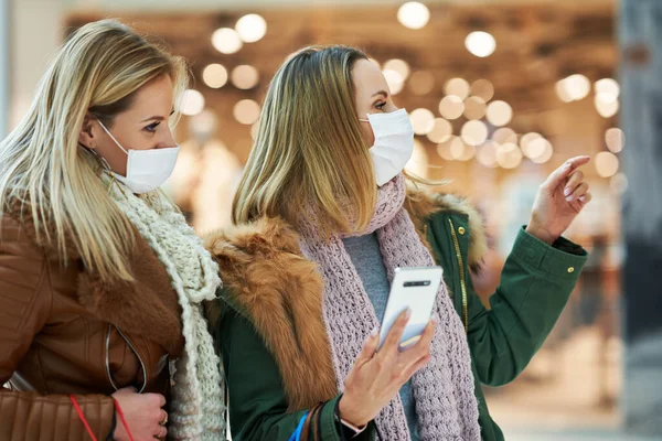 Flickvänner med smartphone shopping tillsammans bär mask coronavirus koncept — Stockfoto