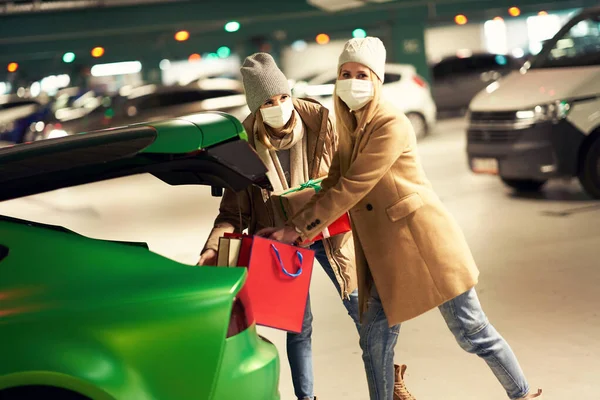 Dwie kobiety z torbami na zakupy w maskach na podziemnym parkingu — Zdjęcie stockowe