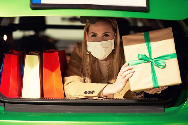 Femme adulte avec des sacs à provisions dans le masque couché dans le coffre — Photo