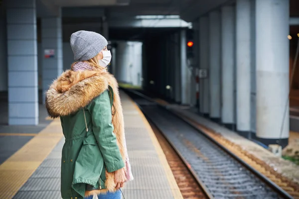 電車の駅での大人の女性は、 covid-19制限のためマスクを着用 — ストック写真