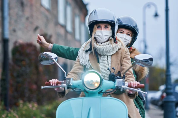 Due donne che indossano maschere e pendolarismo su scooter — Foto Stock